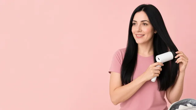Mulher de cabelo preto e liso secando o cabelo com um secador compacto.